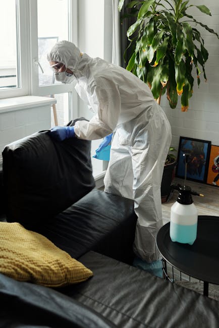A contemporary bedroom featuring a large, neatly made bed with a beige upholstered headboard and a white textured bedspread. Flanking the bed are two matching dark-colored nightstands with sleek gold
